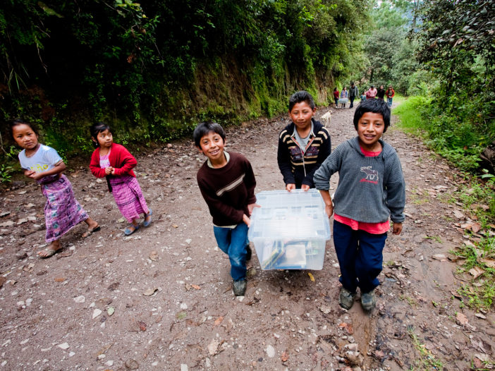 Children carry books to remote village school